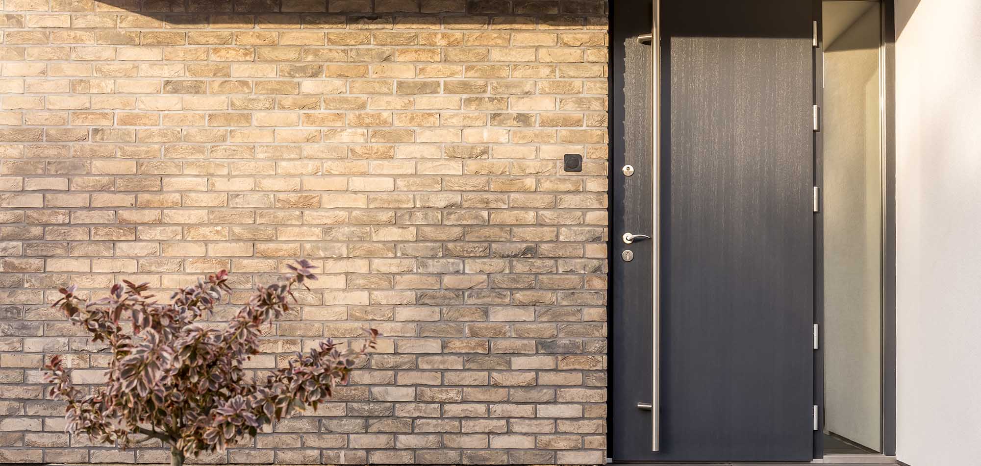 Dark composite door on the front of brick house